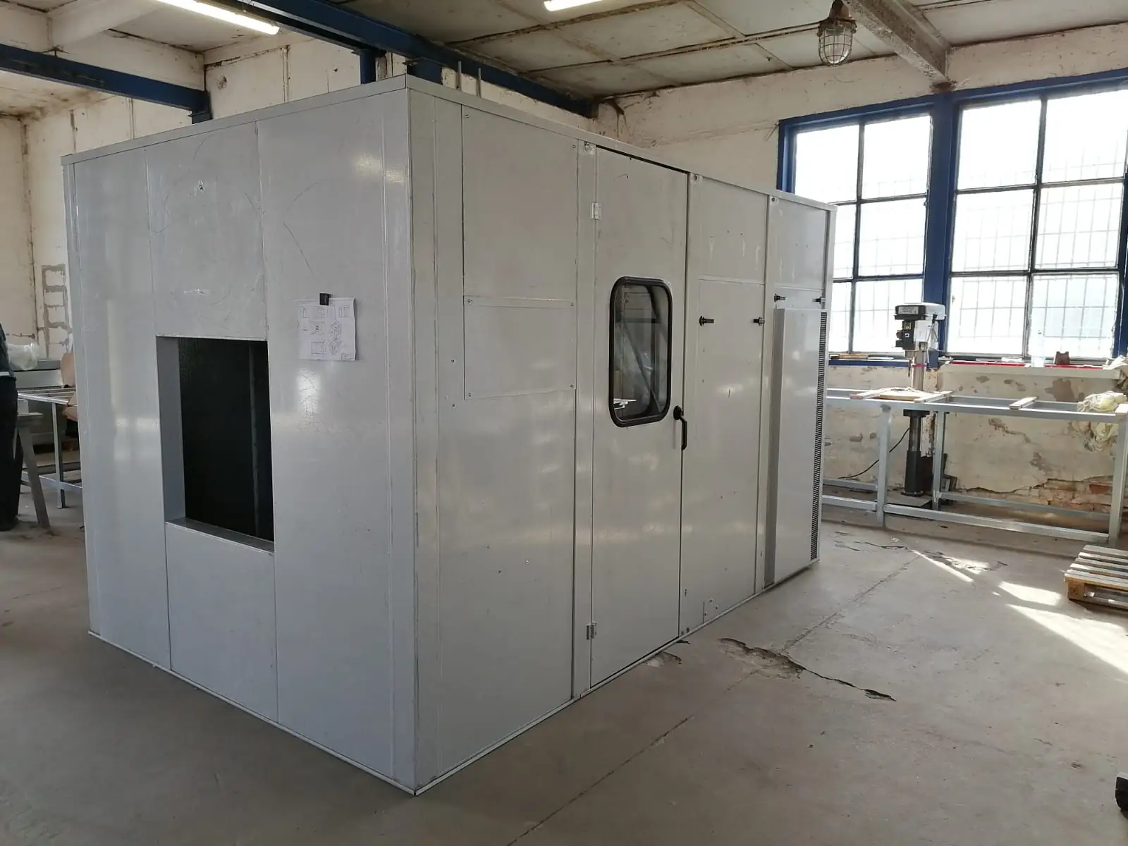 Acoustic enclosure with door, viewing window, and ventilation opening for an industrial machine